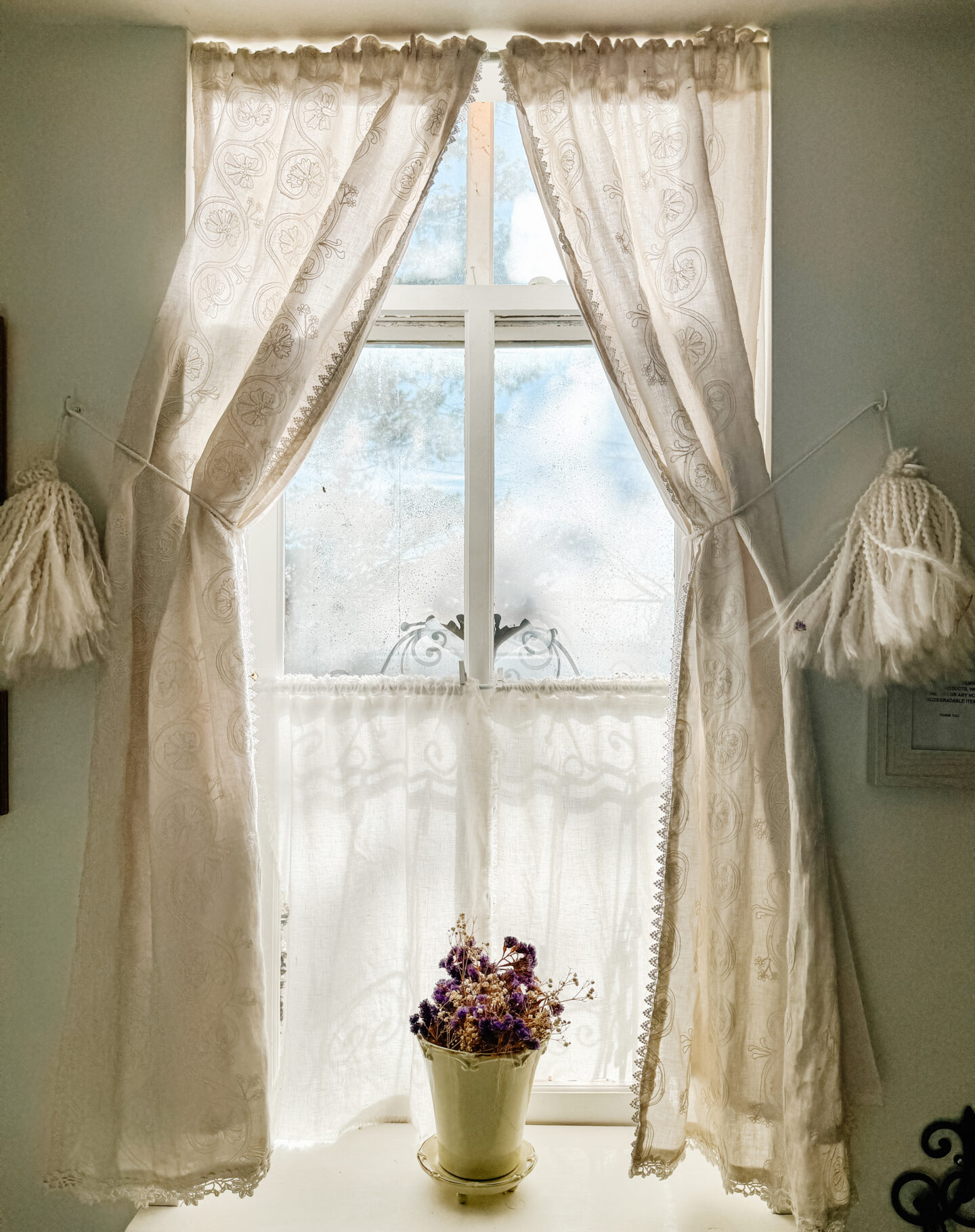 a view from an old window with delicate curtains