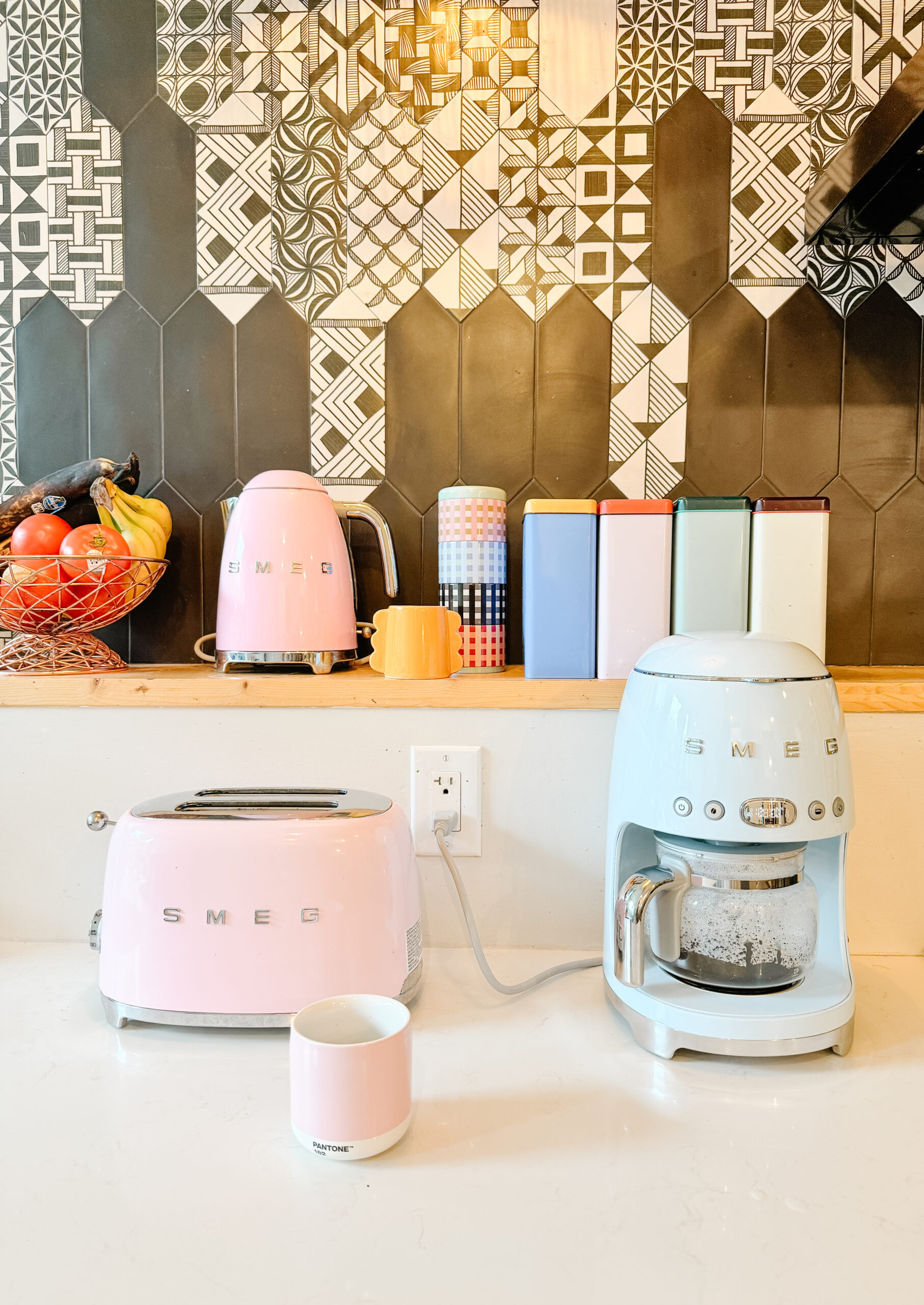 smeg toaster, smeg coffee drip machine on a kitchen counter with black and white tiles