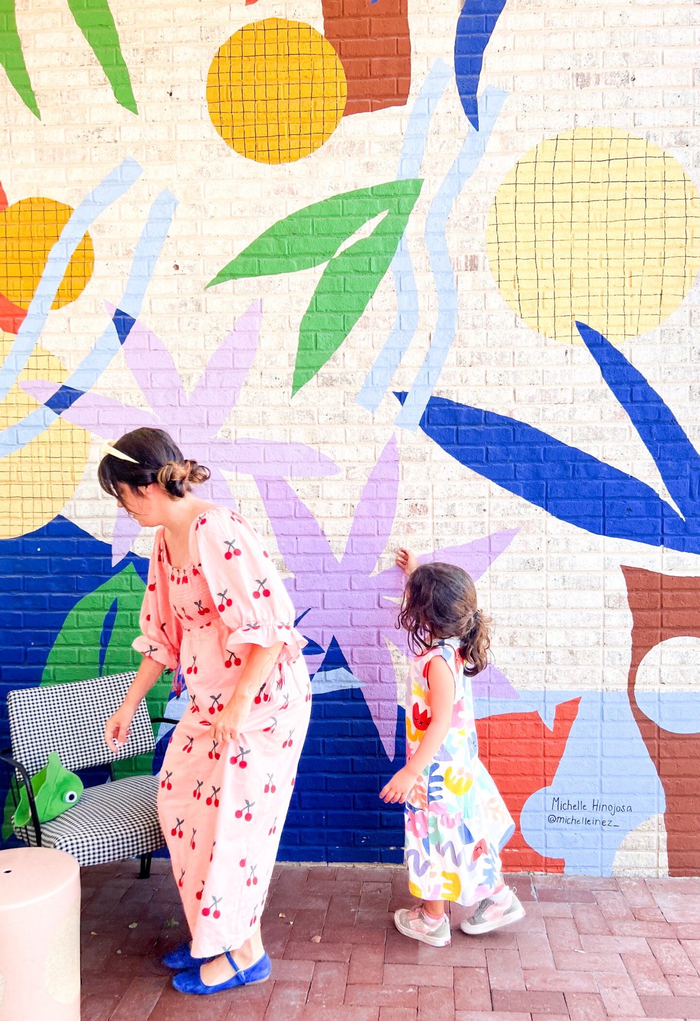 Mom and daughter posing in front of a colorful mural, celebrating art and creativity in parenting